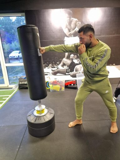 Junger Mann in Trainingskleidung schlägt auf einen Boxsack.