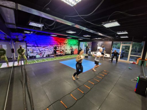 Personen trainieren in einem Fitnessstudio mit verschiedenen Übungsgeräten und bunten Wänden.