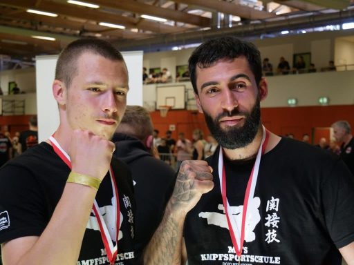 Zwei kampfsportler mit Medaillen, die ihre Fäuste zur Feier heben.