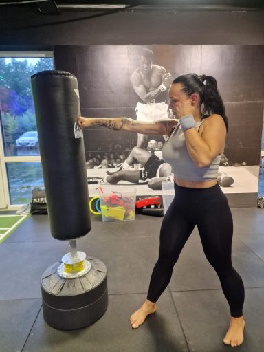 Frauenfitness: Eine Frau schlägt auf einen Boxsack in einem modernen Gym.