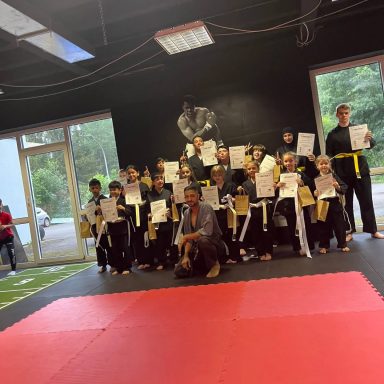 Gruppe von Kindern in schwarzen und gelben Martial-Arts-Anzügen mit Urkunden.