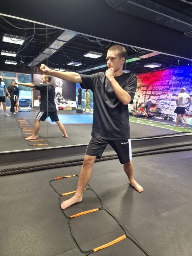 Junger Mann in Sportkleidung führt einen Punch-Trainingsschlag aus.